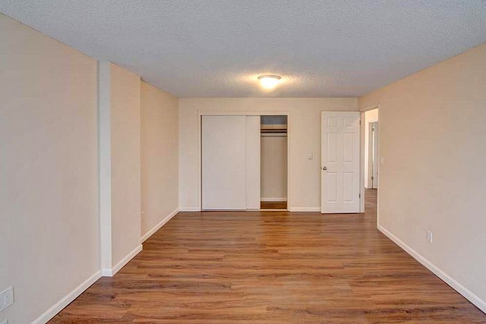 Spacious room with elegant wood flooring and ample closet space, ideal for a modern apartment living.