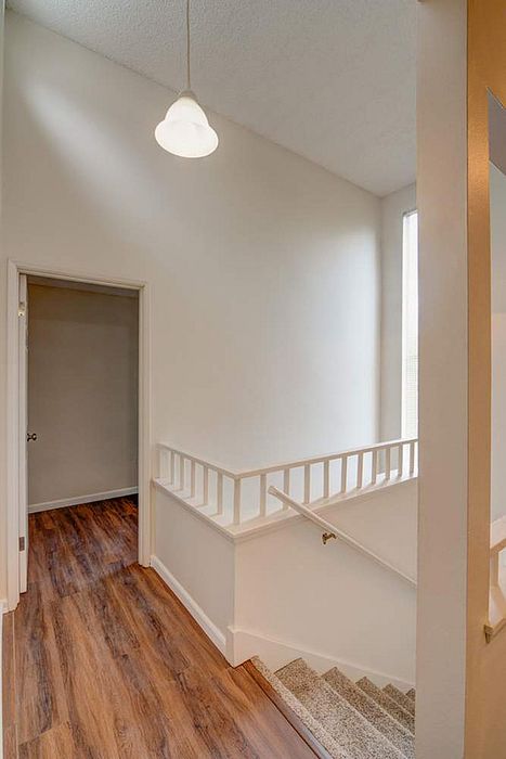 Bright and inviting stairway landing with elegant wood flooring and modern pendant lighting.