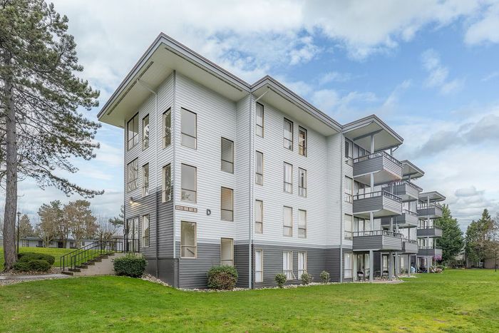 Charming multi-level apartment building with spacious balconies, surrounded by lush greenery and a serene environment.