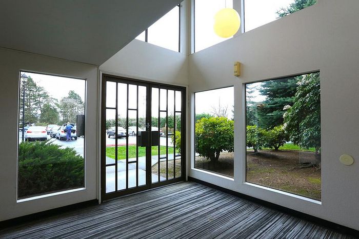 Bright and inviting entrance with large windows overlooking lush greenery and a well-maintained parking area.