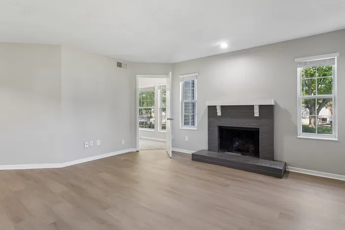 Inviting living room with elegant hardwood flooring, a cozy fireplace, and ample natural light from large windows.