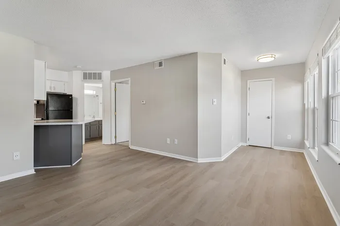 Modern apartment interior with sleek hardwood flooring, open-concept layout, and natural light flooding through large windows.