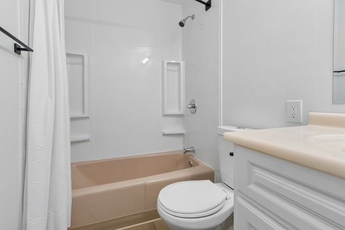 Sleek and modern bathroom with elegant beige fixtures, a shower-tub combo, and a chic white vanity.