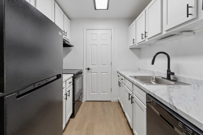 Sleek modern kitchen with white cabinets, marble countertops, and stainless steel appliances offering a stylish culinary space.