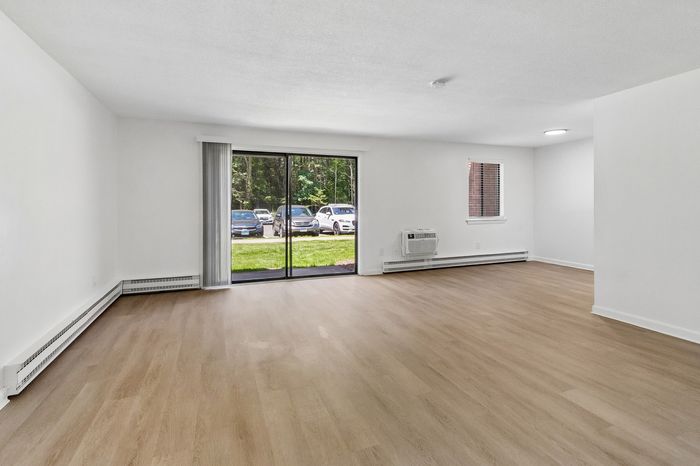 Bright, open-concept living area with elegant wooden flooring and large sliding doors leading to a lush garden view.