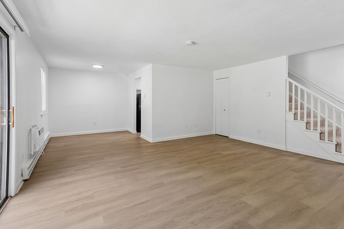 Spacious and bright living area with elegant wooden flooring and modern design, featuring a staircase and large windows.