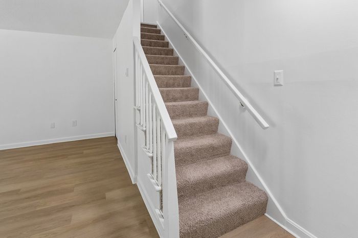 Modern apartment with elegant carpeted staircase and sleek hardwood flooring, inviting a touch of luxury and style.