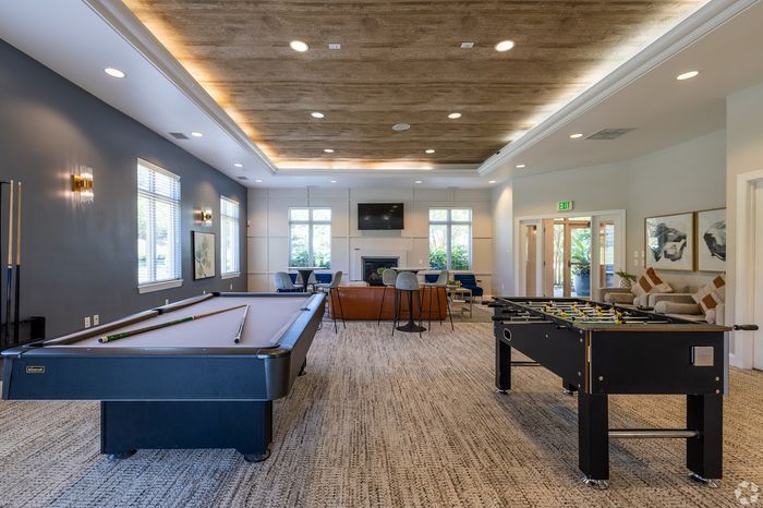 Modern entertainment area featuring a pool table, foosball, and a cozy seating lounge with a fireplace and TV, ideal for social gatherings.