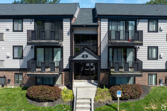 Charming and modern apartment facade with private balconies, surrounded by lush greenery and manicured landscaping.
