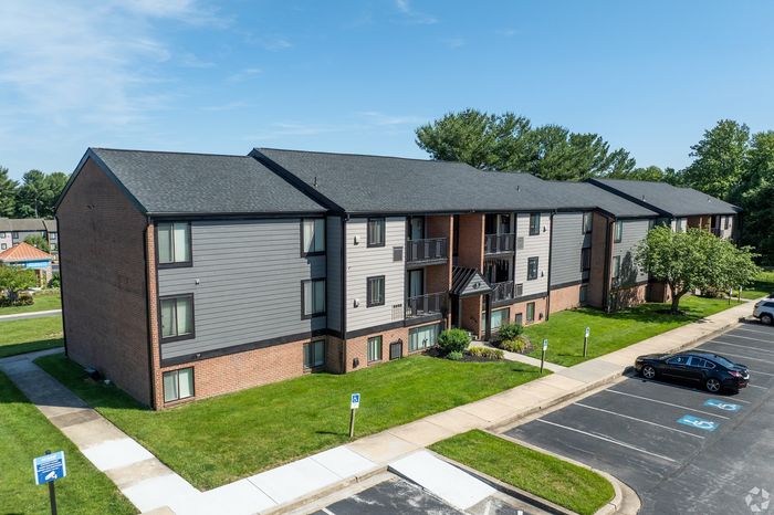 Charming apartment building with modern exterior, surrounded by well-maintained green lawns and convenient parking.