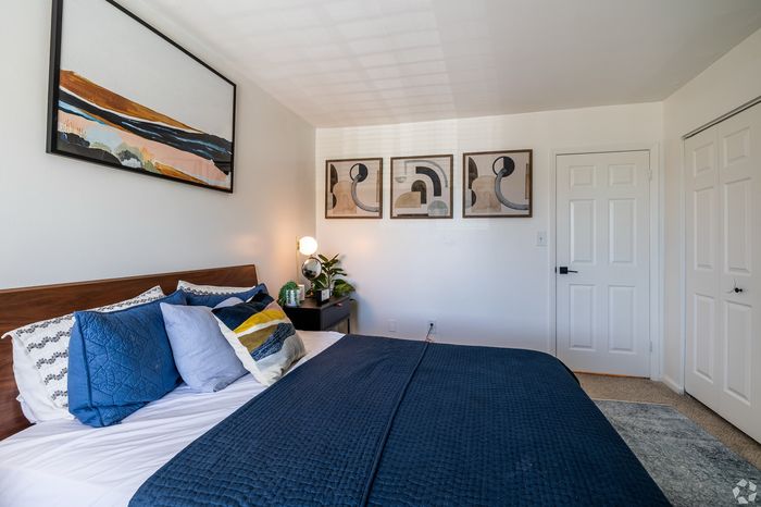 Elegant bedroom with modern art, cozy pillows, and a warm atmosphere, perfect for relaxation.