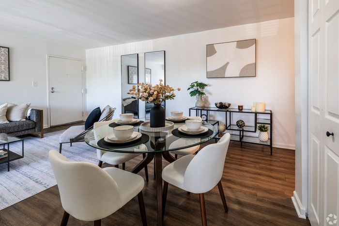 Elegant dining area in a modern apartment with sleek glass table, stylish seating, and contemporary decor.