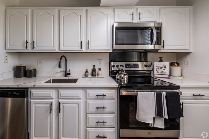 Contemporary kitchen with sleek stainless steel appliances, elegant white cabinetry, and modern black fixtures.