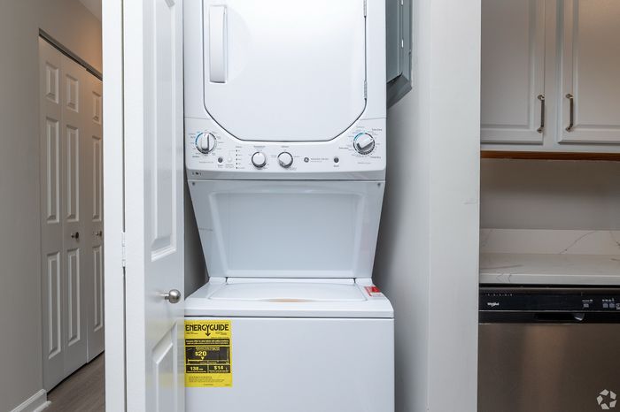 Compact laundry area with modern stacked washer and dryer, adjacent to sleek kitchen cabinetry.