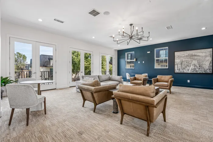 Elegant living room with stylish leather seating, modern chandelier, and expansive windows offering serene views.