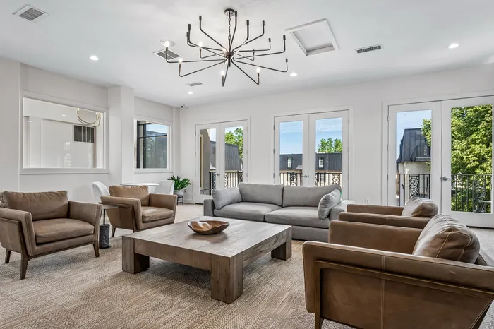 Elegant living room with modern chandelier, plush seating, and natural light from large windows offering scenic views.
