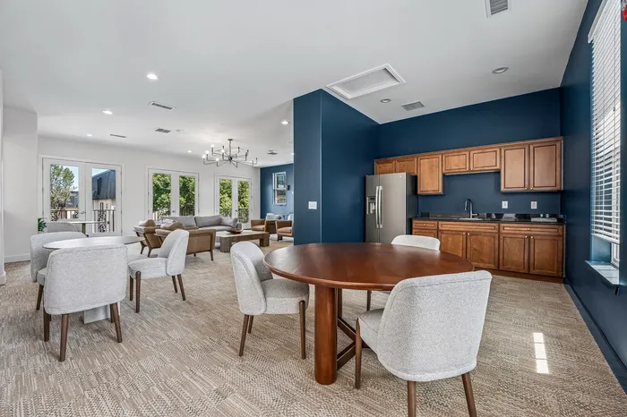 Elegant open-plan living area featuring modern furnishings, vibrant blue walls, and a well-equipped kitchen, perfect for hosting gatherings.
