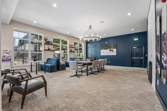 Elegant and inviting communal lounge with stylish seating, large windows providing natural light, and a stunning chandelier centerpiece.
