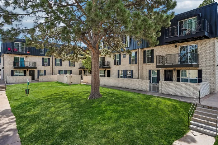 Charming apartment building with balconies and lush green courtyard, perfect for modern living and relaxation.
