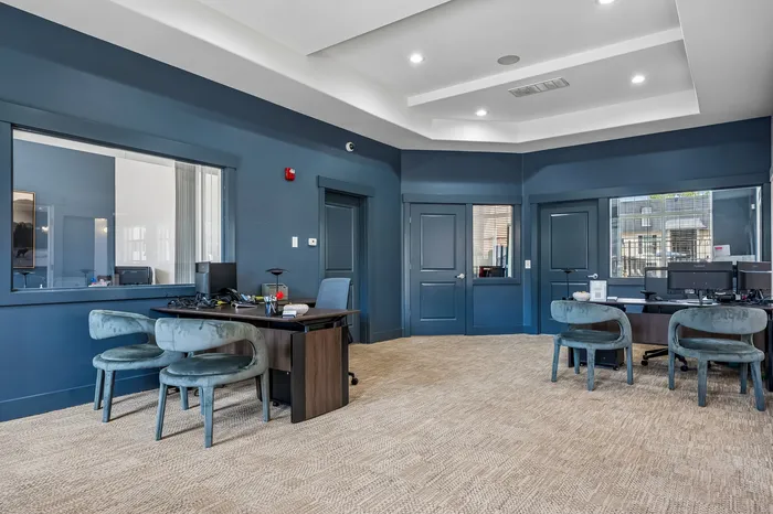 Modern office space with elegant blue walls, chic furniture, and ample natural light for a productive workspace.