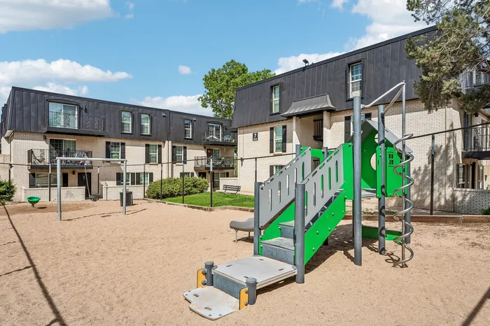 Charming apartment complex featuring modern architecture with private balconies, set amidst lush greenery and a playful children's playground.