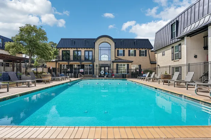 Luxurious apartment complex with a pristine swimming pool, surrounded by elegant architecture and inviting lounge chairs.