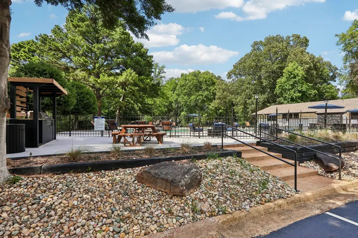 Charming outdoor recreational area with a picnic table, surrounded by lush greenery and equipped with a barbecue grill station.