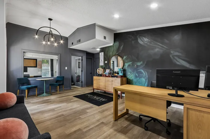 Chic office space with modern lighting, elegant wood flooring, and a stylish accent wall featuring floral art.