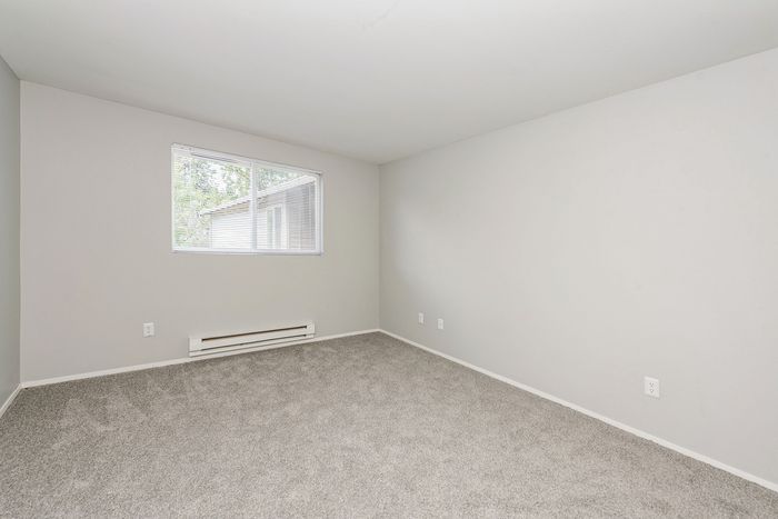 Bright, newly carpeted room with large window offering natural light and serene views.