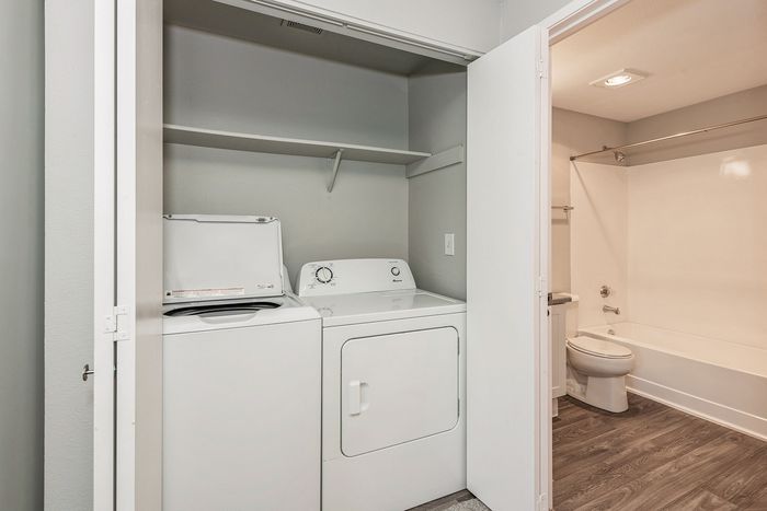 Modern apartment featuring a convenient in-unit laundry area with washer and dryer next to a sleek bathroom with updated fixtures.