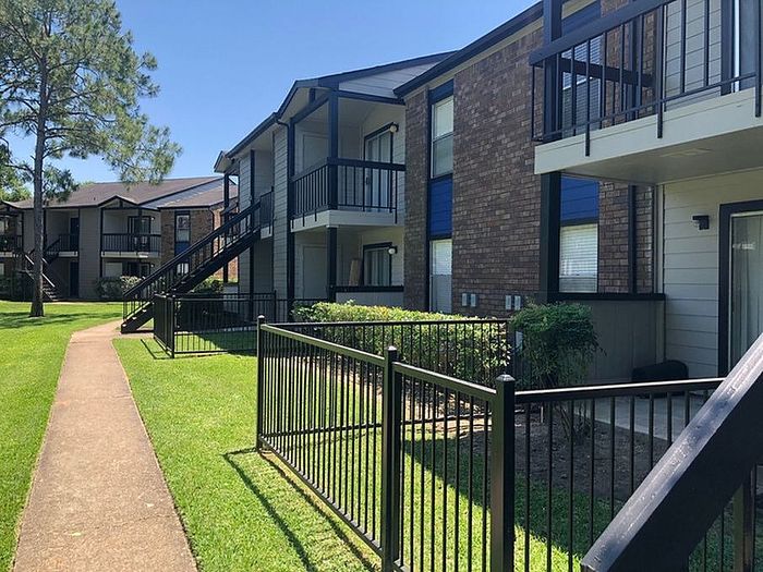 Charming apartment complex with brick fa&ccedil;ade, private balconies, and scenic green surroundings, perfect for comfortable living.