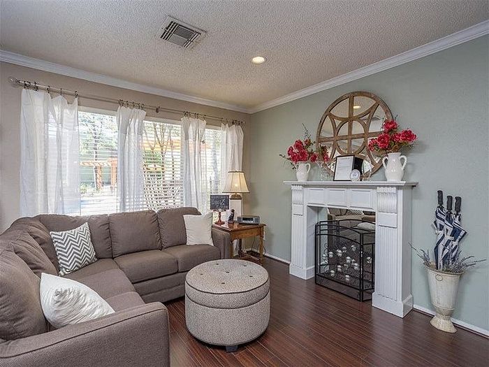Inviting living room with a cozy sectional sofa, elegant fireplace, and chic decor featuring vases and vibrant flowers, perfect for relaxation and entertaining.