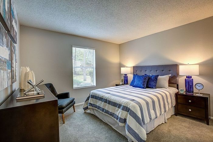 Bright and inviting bedroom featuring a plush bed with striped linens, warm lighting, and elegant decorative accents for a cozy retreat.