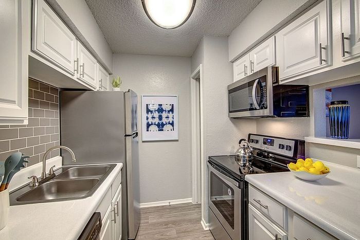 Modern kitchen with sleek stainless steel appliances, white cabinetry, and chic gray backsplash, exuding a contemporary and inviting atmosphere.