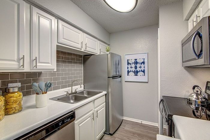 Modern kitchen with sleek stainless steel appliances, elegant white cabinetry, and stylish backsplash.