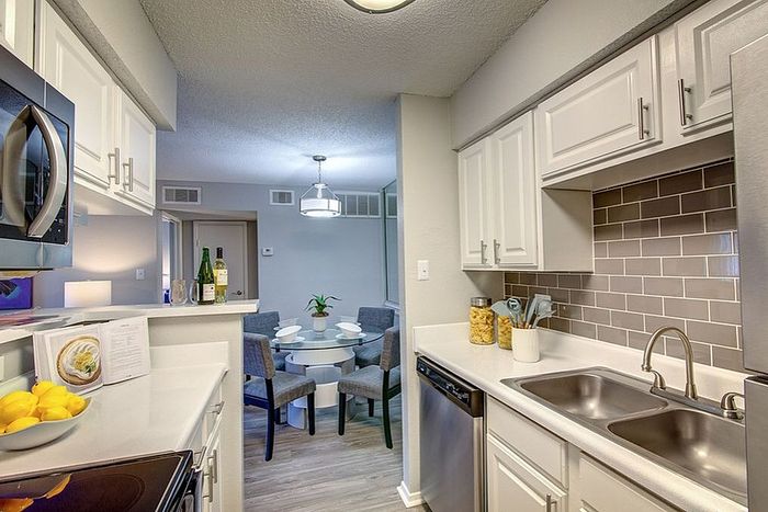 Contemporary kitchen with sleek white cabinetry, modern appliances, and a cozy dining area, exuding a welcoming ambiance.