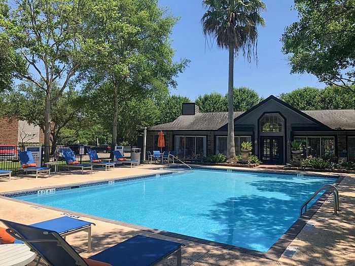 Charming residential pool area with inviting lounge chairs, surrounded by lush greenery and a cozy clubhouse.