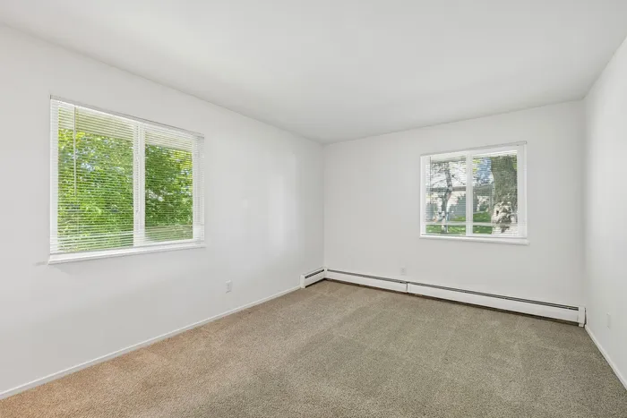 Bright and spacious bedroom with large windows, offering abundant natural light and serene outdoor views.