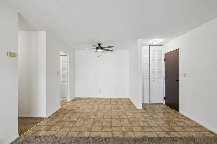 Bright and spacious entryway with modern ceiling fan, featuring tile flooring and ample closet space.