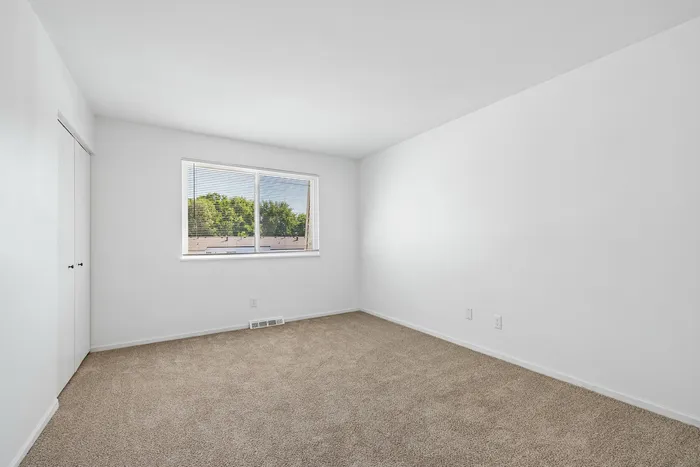 Bright and airy bedroom with plush carpeting and a large window offering scenic views.