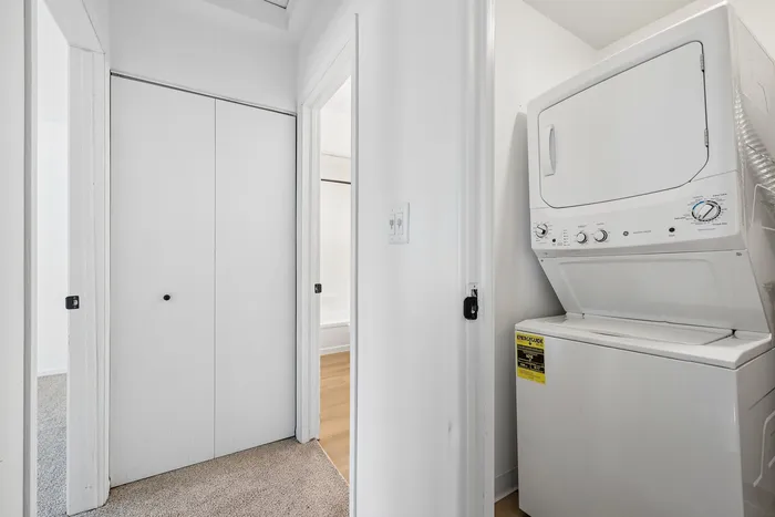 Bright hallway featuring in-unit stacked washer and dryer adjacent to pristine bathrooms, offering modern convenience.