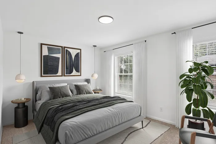 Elegant bedroom with modern decor, featuring a cozy gray bed, stylish abstract artwork, and bright natural light from large windows.