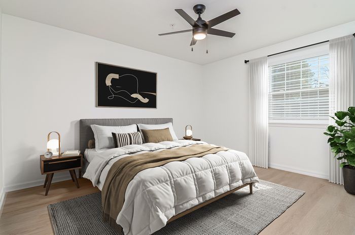 Bright and cozy bedroom with modern decor, featuring a comfortable bed, stylish artwork, and abundant natural light from a large window.