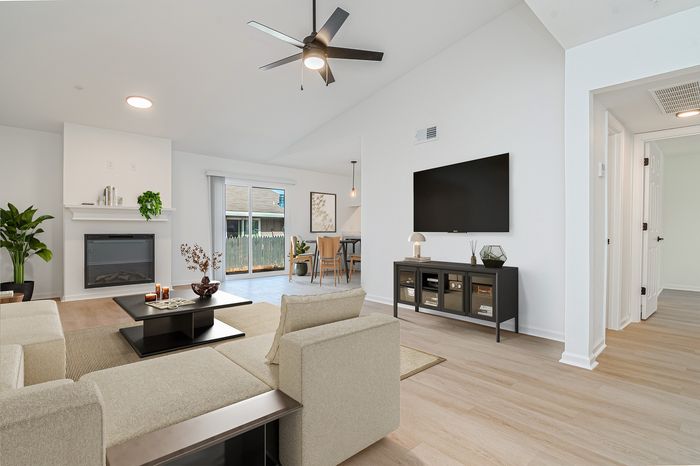 Modern living room with sleek furniture, featuring a cozy fireplace, elegant lighting, and glass doors opening to a serene outdoor space.