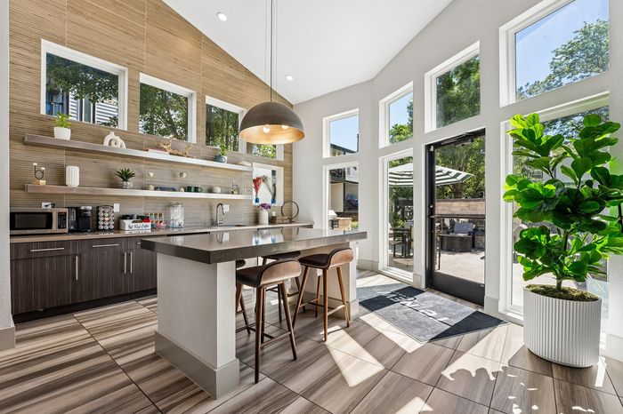 Bright and modern kitchen with sleek island, stylish open shelves, and large windows inviting natural light.