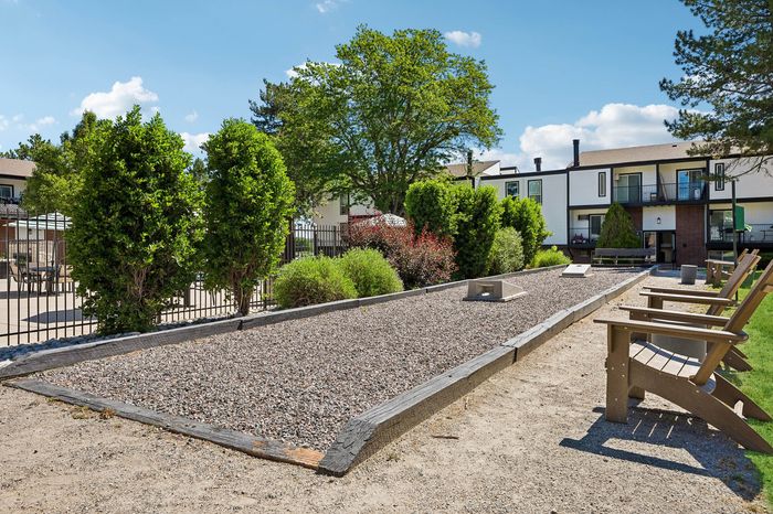 Inviting outdoor area with a well-maintained bocce court, lush greenery, and comfortable seating, perfect for relaxing in a vibrant community setting.