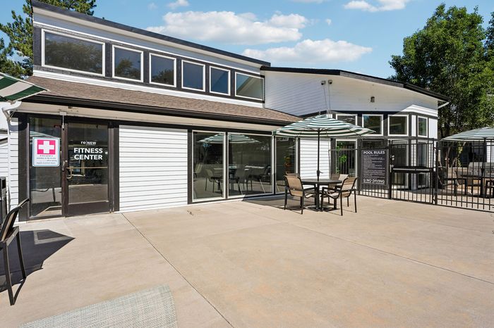 Chic apartment amenities featuring a modern fitness center and poolside patio with stylish seating and umbrellas.