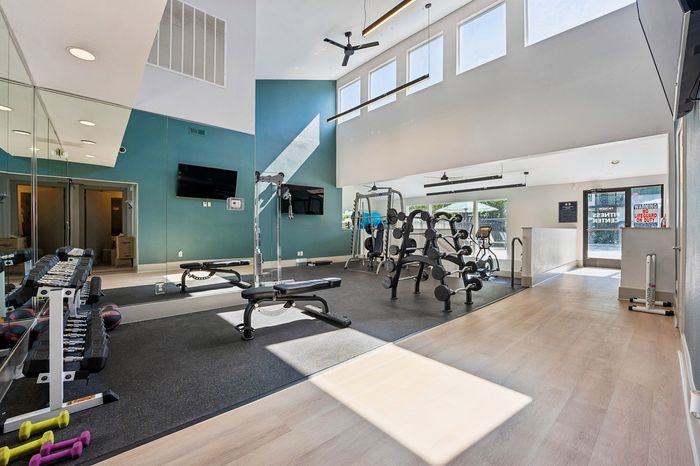 Bright and modern fitness center with sleek equipment, high ceilings, and vibrant teal accents, ideal for an energizing workout.