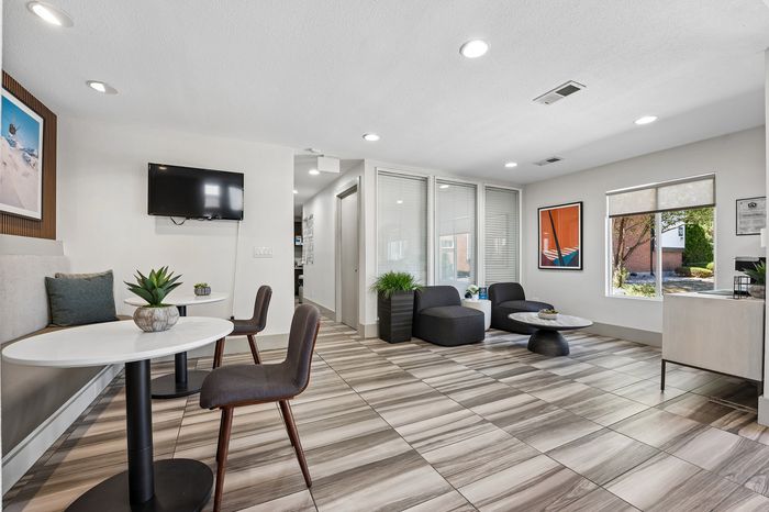 Modern lounge area featuring cozy seating, sleek tables, and natural light from large windows, perfect for relaxation and social gatherings.