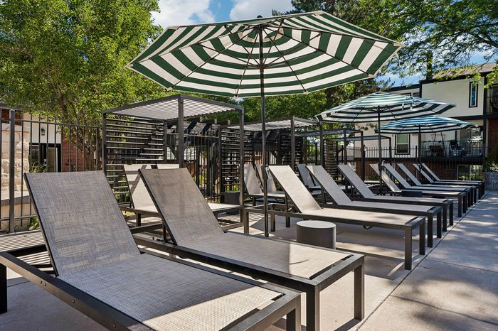Inviting outdoor lounge area featuring stylish sun loungers under chic striped umbrellas, perfect for relaxation and comfort.